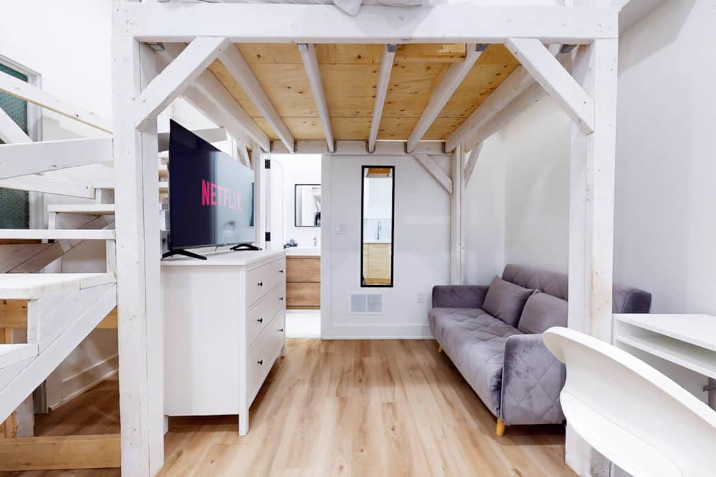 Living room with a platform bed above it