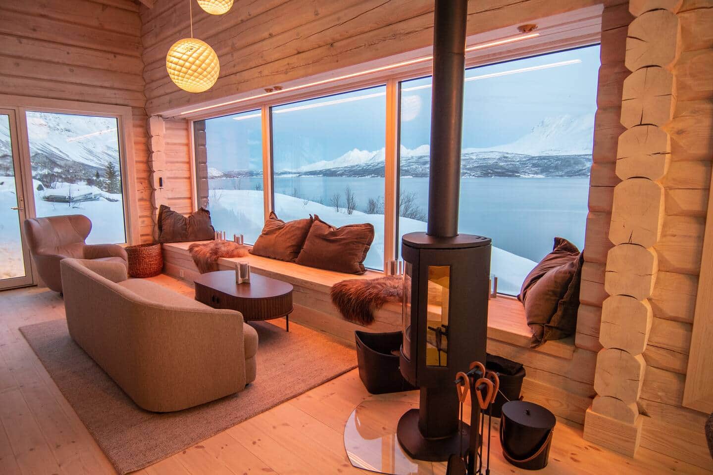 Große Fensterfront mit Ausblick auf verschneite Fjordlandschaft – stilvoller Rückzugsort