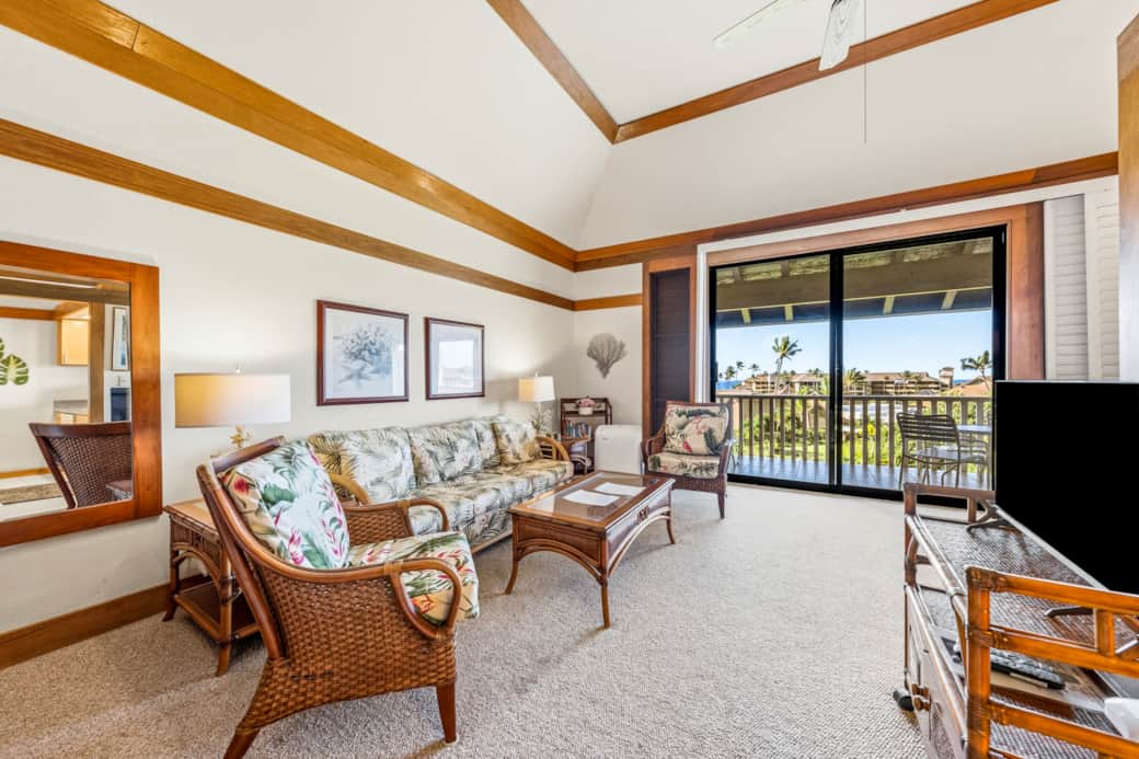 Bright tropical living space with vaulted ceilings and a lanai overlooking lush palms.