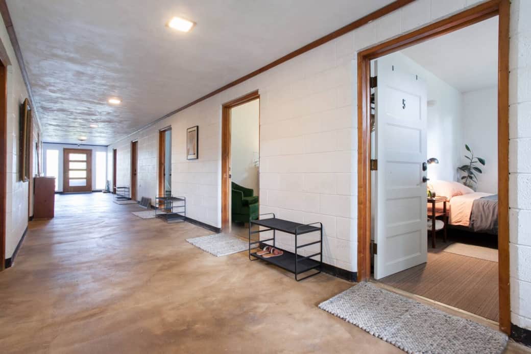 This VERY wide large hallway currently has 4 bedrooms to the right and another bedroom, kitchen, linen closet, bathroom and ramp to the den on the left. In this photo you are looking at the front door, the back door is behind the photographer. 