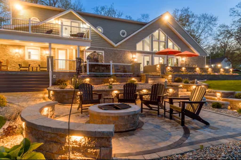 Cozy fire pit glows under night sky, surrounding it by a curved seating bench.