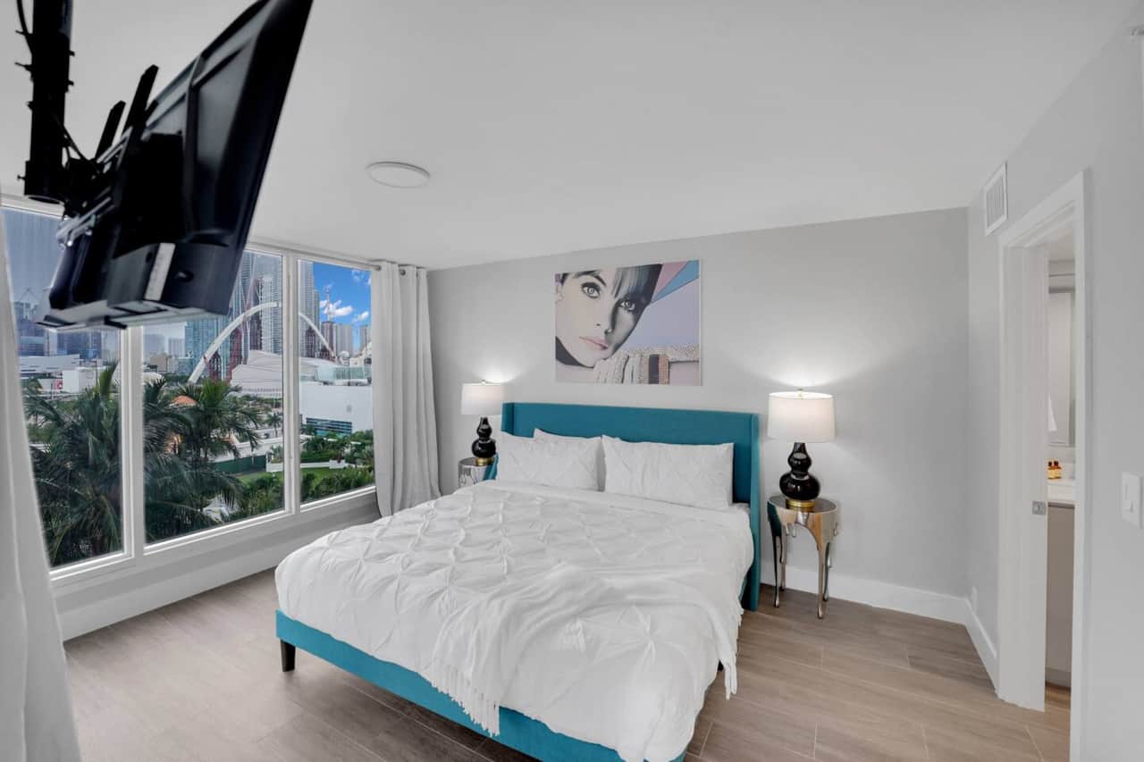 1st Bedroom with attached bathroom (smaller of two bedrooms). king bed, Roku streaming tv, walk in closet, balcony access, views of Miami skyline and water views of Biscayne Bay