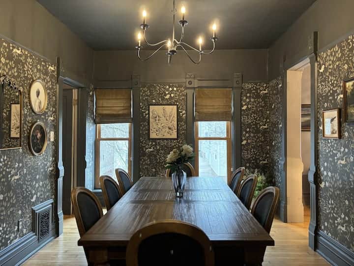 Elegant dining room with statement wallpaper, large windows, and a beautiful wood table