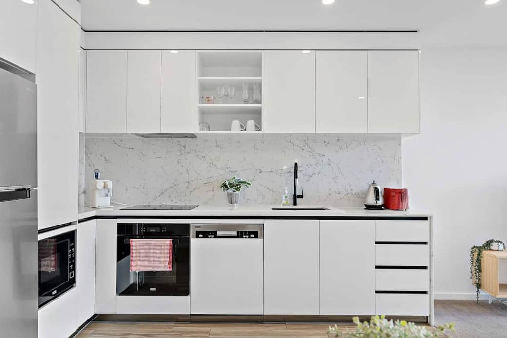 Craft culinary masterpieces in our modern kitchen, designed with sleek white cabinetry and high-end stainless steel appliances. The marble backsplash adds a touch of luxury to your cooking experience.