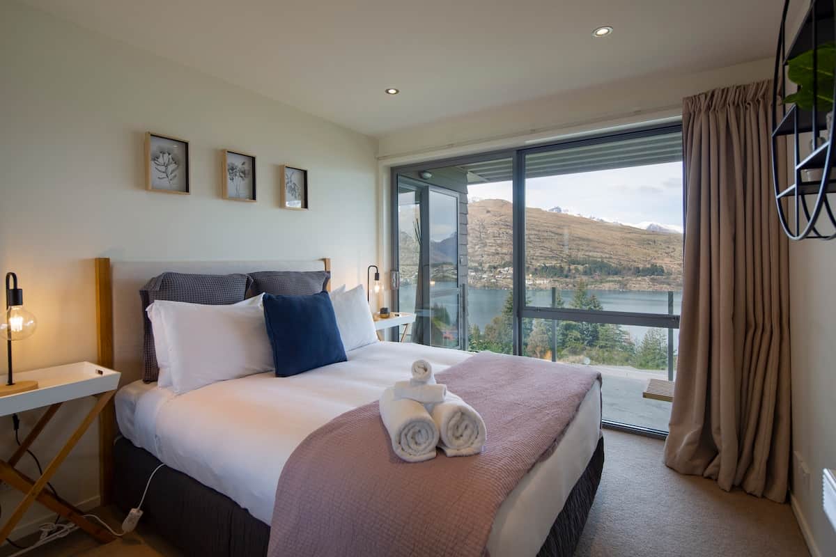 Bedroom one with lake views and access to private balcony
