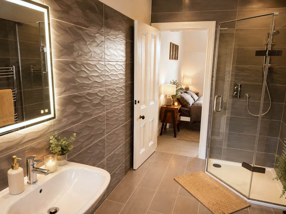 En-suite with an illuminated mirror and corner shower, opening onto the bedroom.
