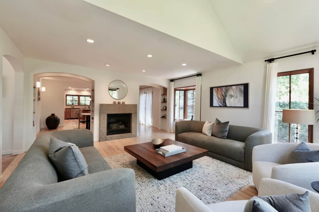 The front entry opens to an expansive, sun-lit living room where a plush sofa setup comfortably seats eight. When the mountain evening air turns chilly, a single touch of a remote ignites the large gas fireplace, casting a cozy glow across the room.