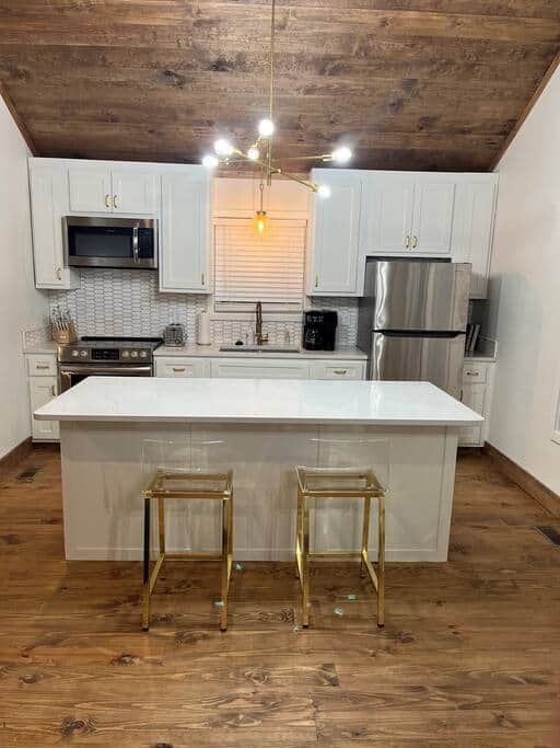 Your kitchen has quartz countertops and island, stainless steel appliances, and gold accent pieces. 