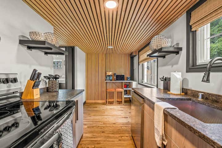 Sleek and modern kitchen with a striking wood-slat ceiling and open shelving.