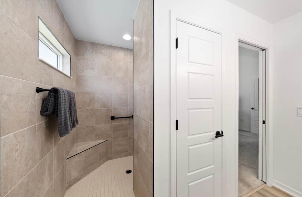 Fully tiled walk in primary shower with linen closet