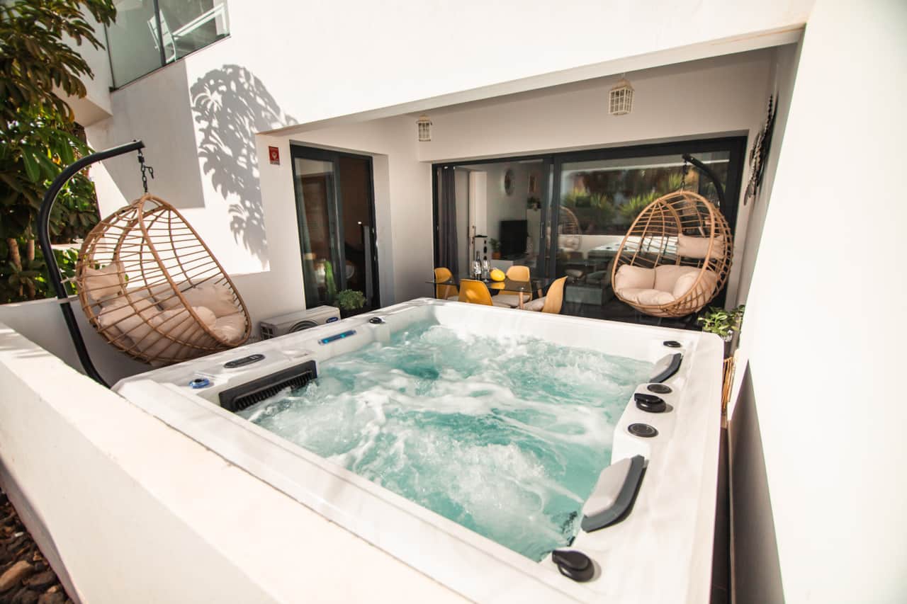 Jacuzzi de gama alta burbujeante en el patio privado con sillones colgantes, planta baja accesible