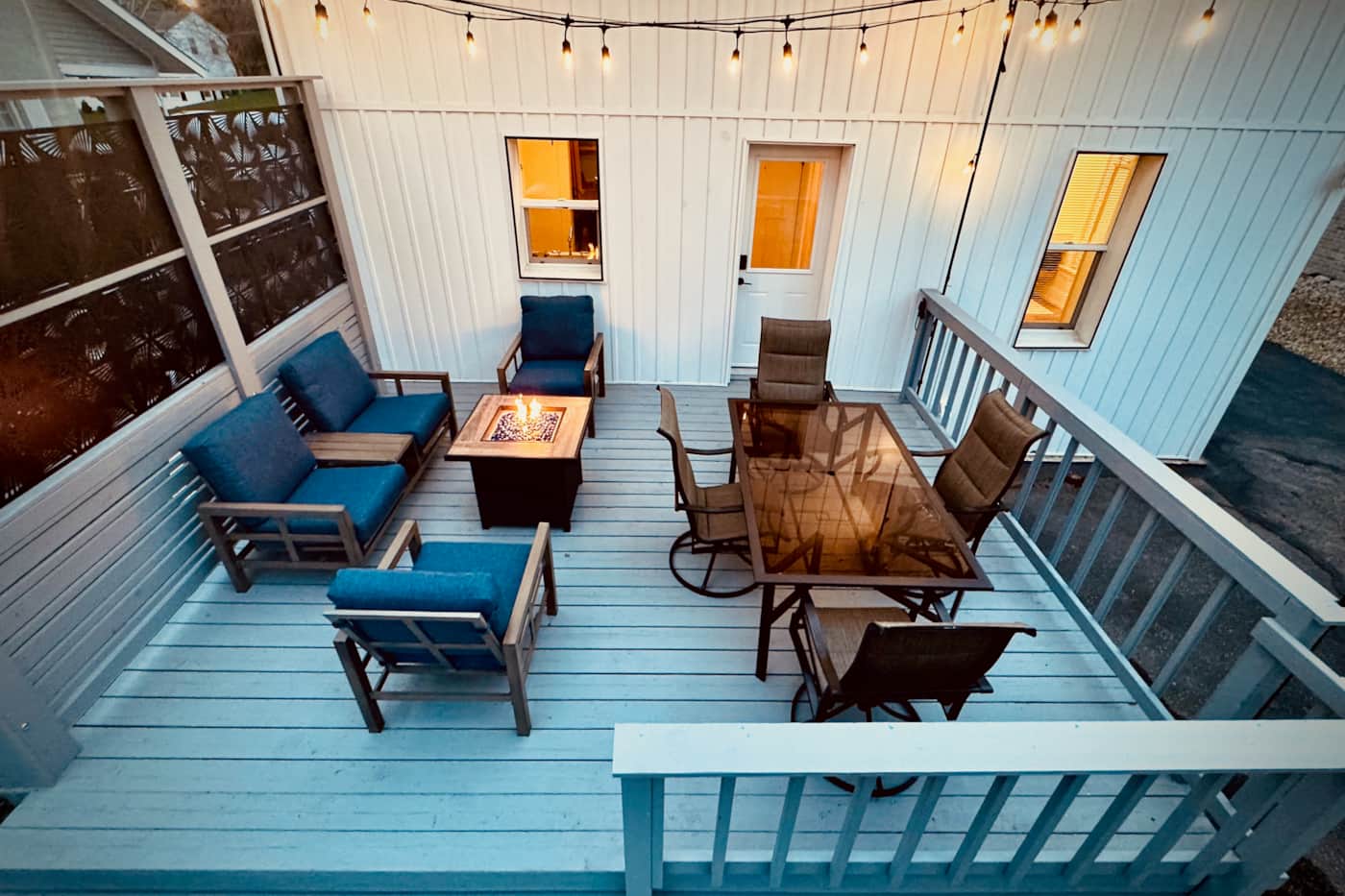 Private back deck with dining, seating, string lights, and fire table at Surf & Serenity House