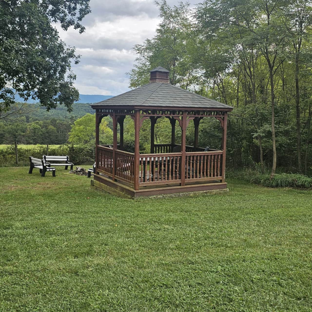 Gazebo in a secluded back corner of the property, with benches and a fire pit nearby