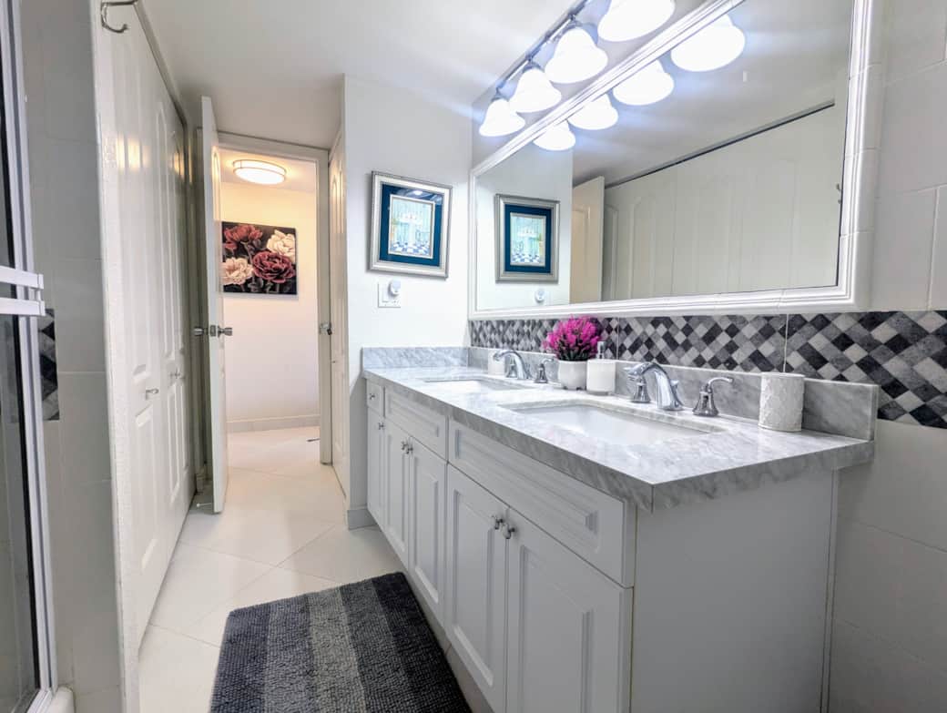 Newly renovated bathroom with double sink, dual shower heads,  and bath tub