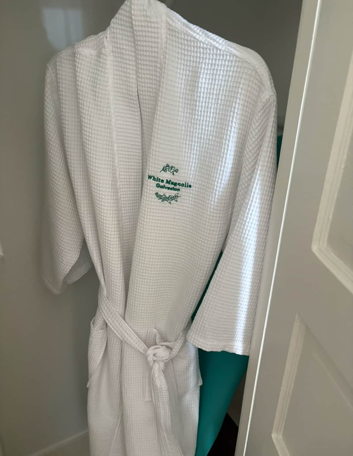Plush bathrobe hanging in a bedroom closet at a Galveston vacation rental for guest use