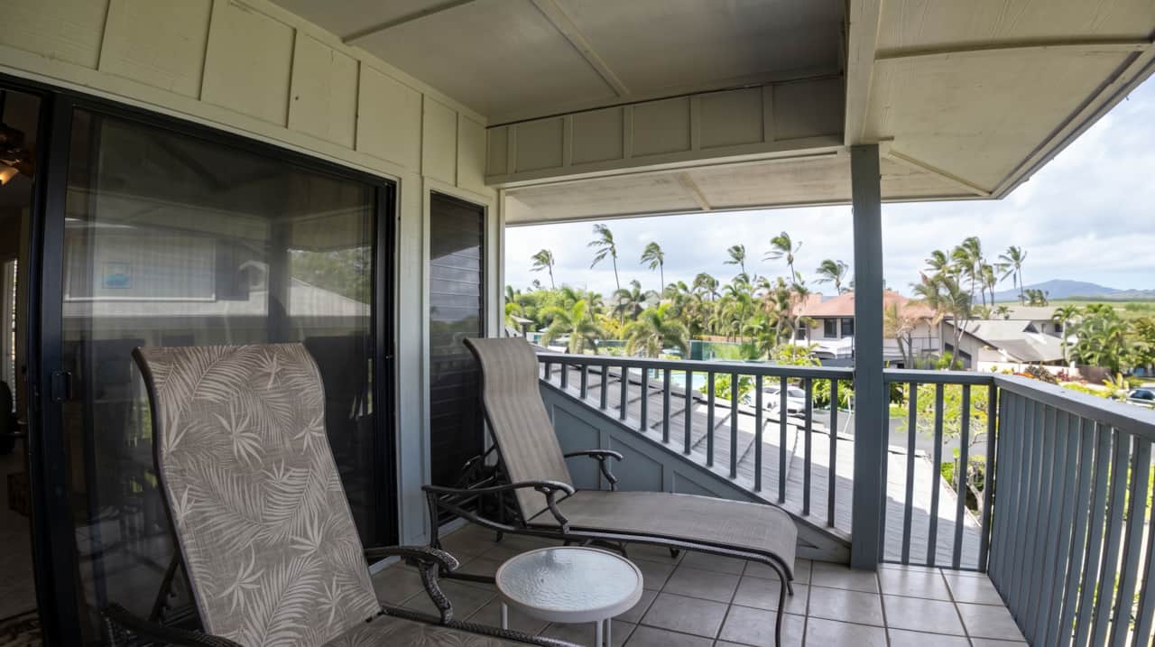 Covered lanai with comfortable seating and relaxing tropical views.