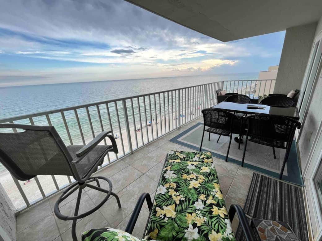 Long view of Gulf side balcony showing dining table, lounge and elevated bar chair.