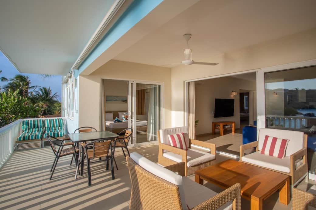 There are sunscreens, a ceiling ventilator, chairs, beach beds and a dinner table on the balcony