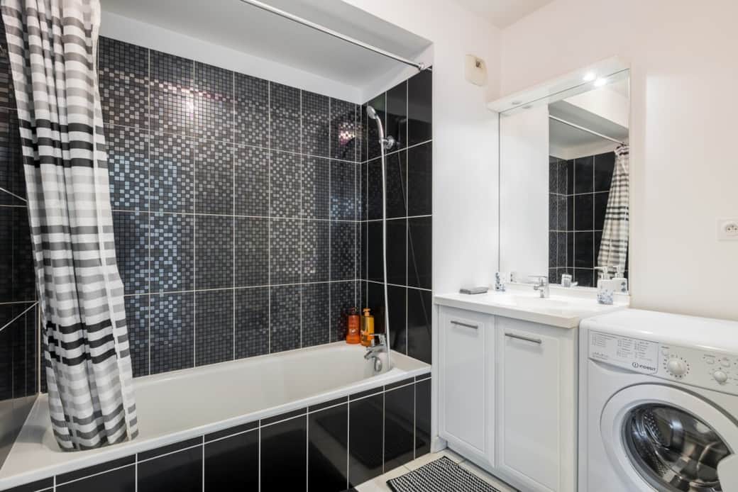 Salle de bain avec baignoire et lave-linge