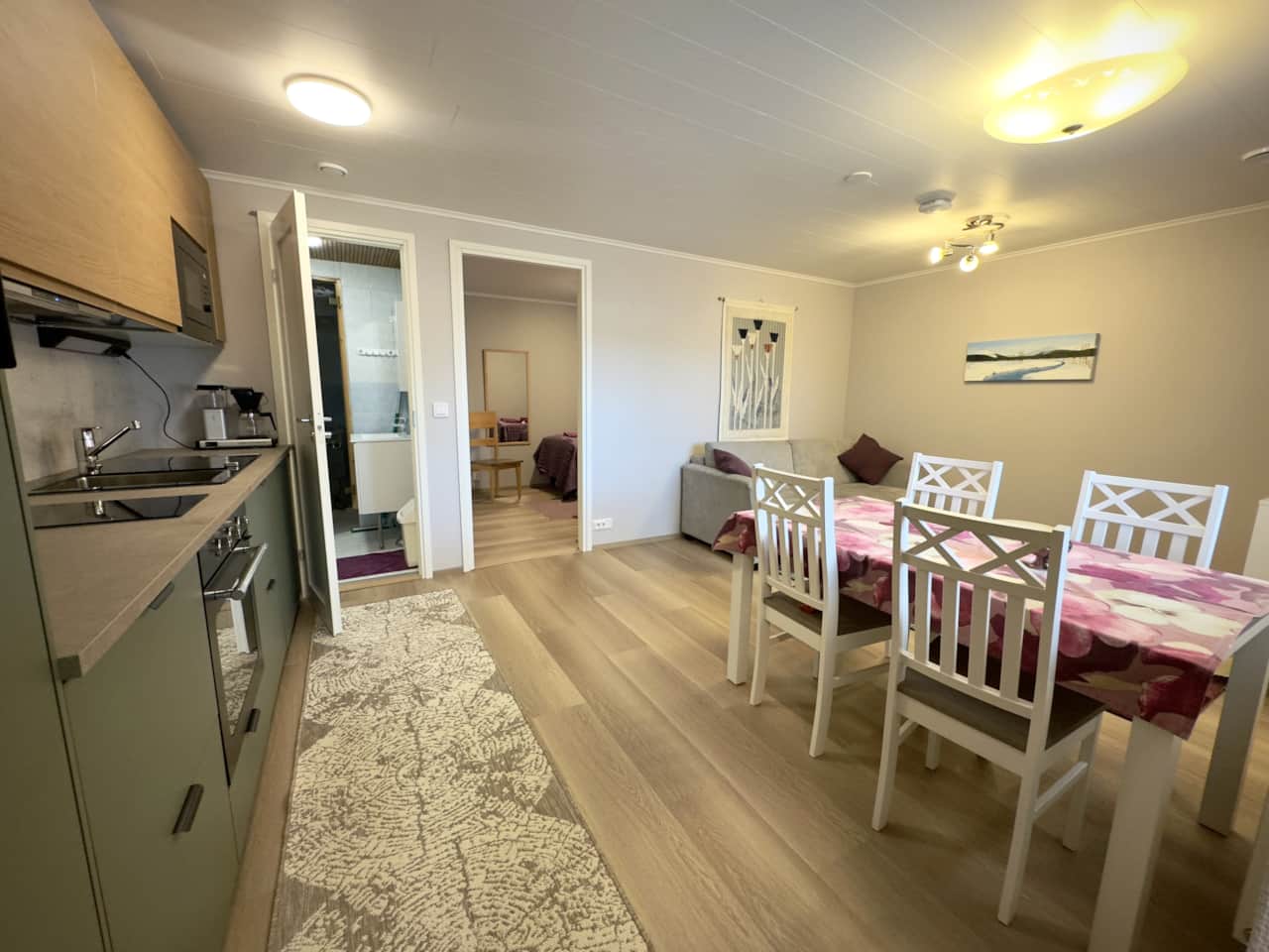 An apartment on the first floor with sauna, sofa, TV, dining area, and a well-equipped kitchen.