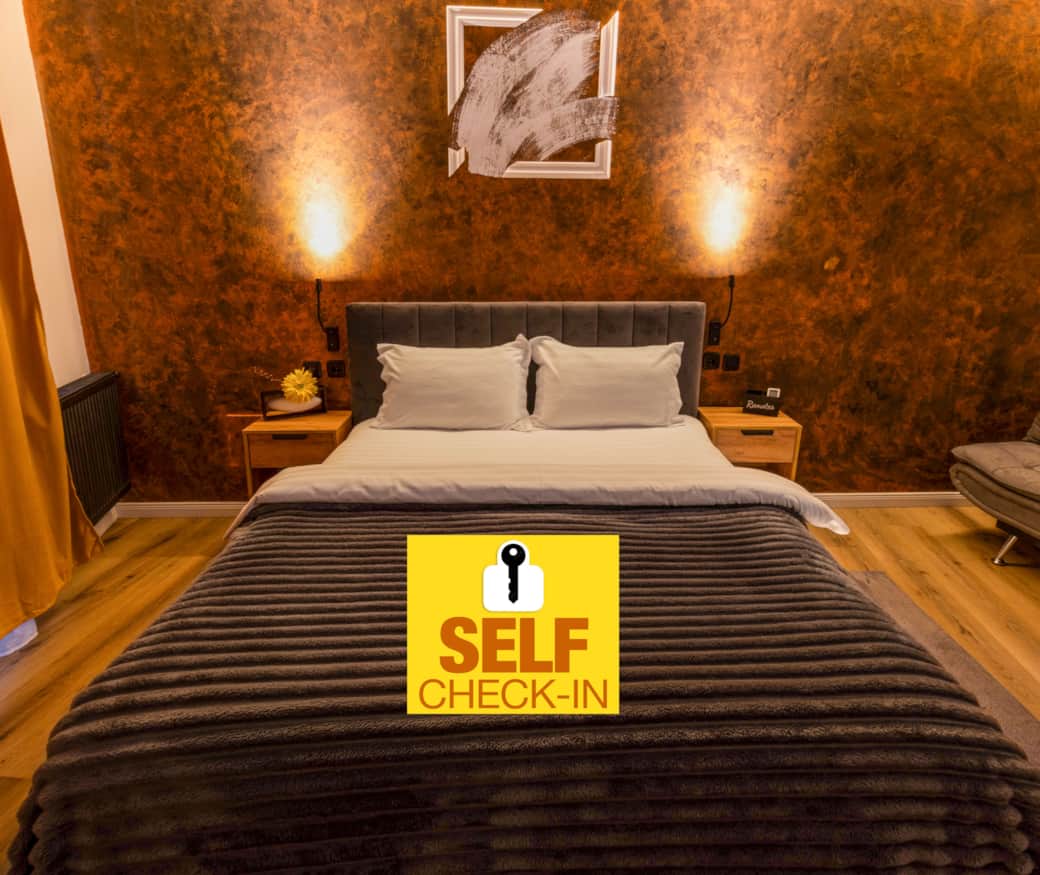 Cozy double bedroom with upholstered headboard, warm ambient lighting, and textured accent wall.