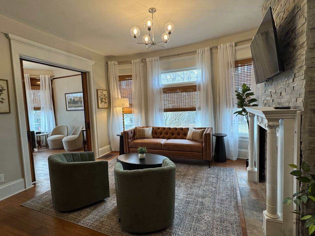 Bright and inviting living space with large bay windows, soft sheer curtains, and natural light.