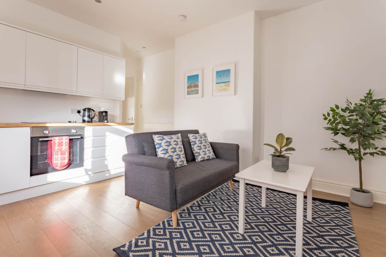 Cosy living area equipped with kitchen facilities, two-person dining table and sofa.