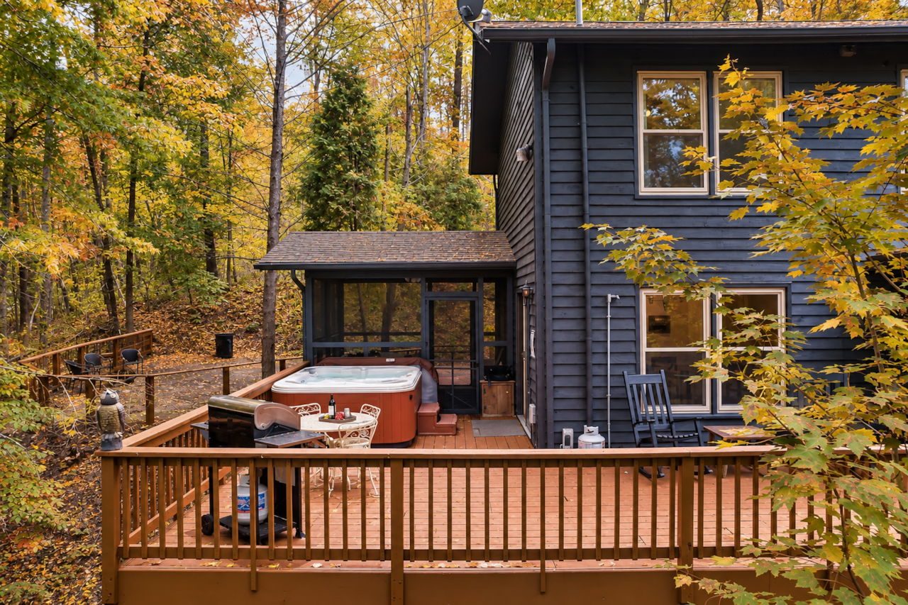 Spacious rear deck with hot tub, outdoor seating, and a quiet wooded setting