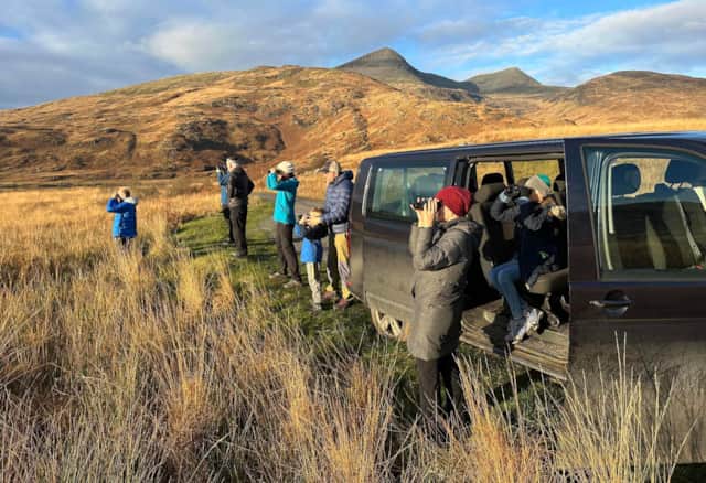 Guests using binoculars beside a Nature Scotland tour vehicle on Mull