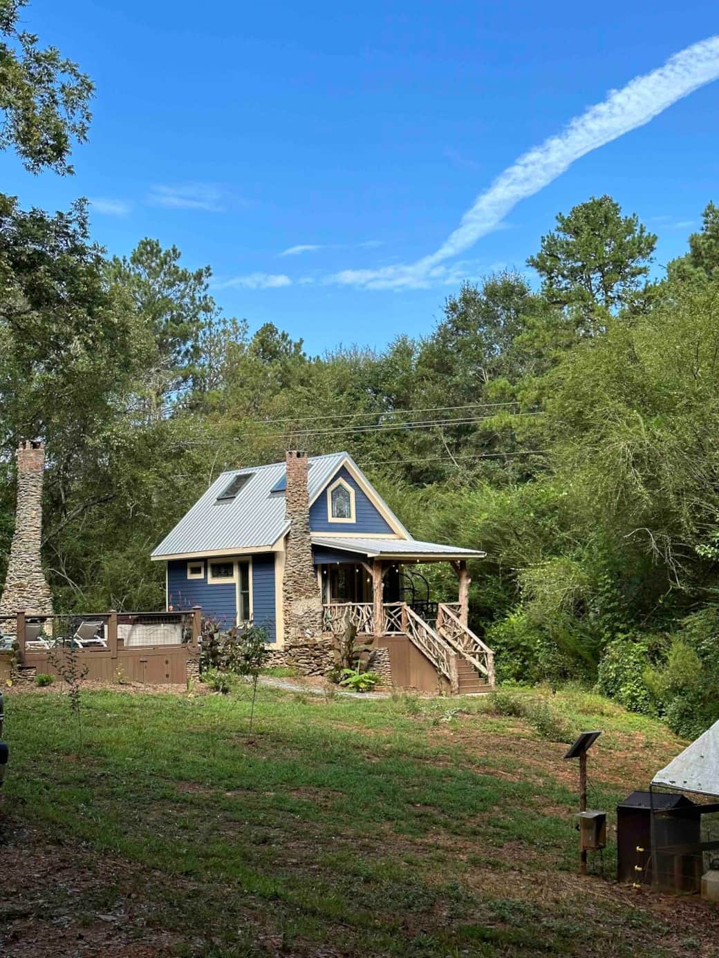 The cabin with it's auxillary entertainment deck with hot tub, griddle, loungers, chairs, outdoor fireplace, and wood fired pizza oven.