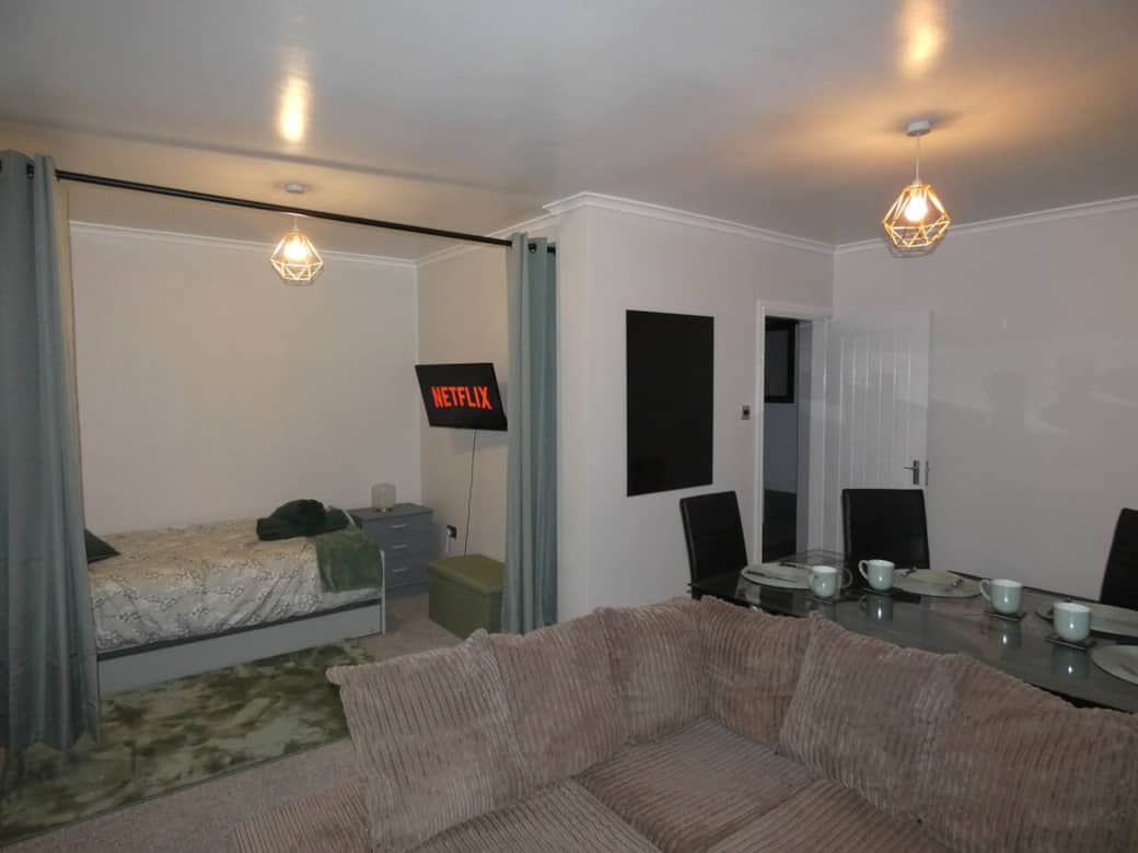 Living room with trundle bed, dining area, sofa and smart TV with wireless mobile screen sharing