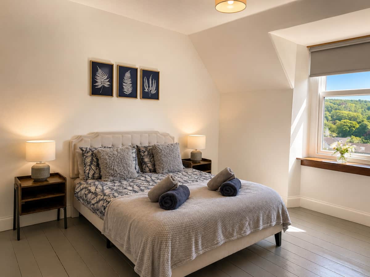 Bedroom 2 with an upholstered bed, fern prints and a dormer window.