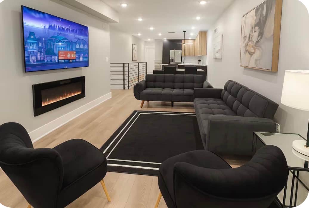 The living room is tastefully furnished with two futon sofa beds, a spacious 65 inch television featuring a wide selection of Ruku channels, and an abundance of invigorating natural light that gracefully floods the room through the large windows.