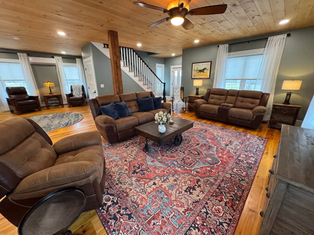 Main level - Relax in the bright, open living room featuring cozy recliners, large sofas, and a stunning farmhouse aesthetic.