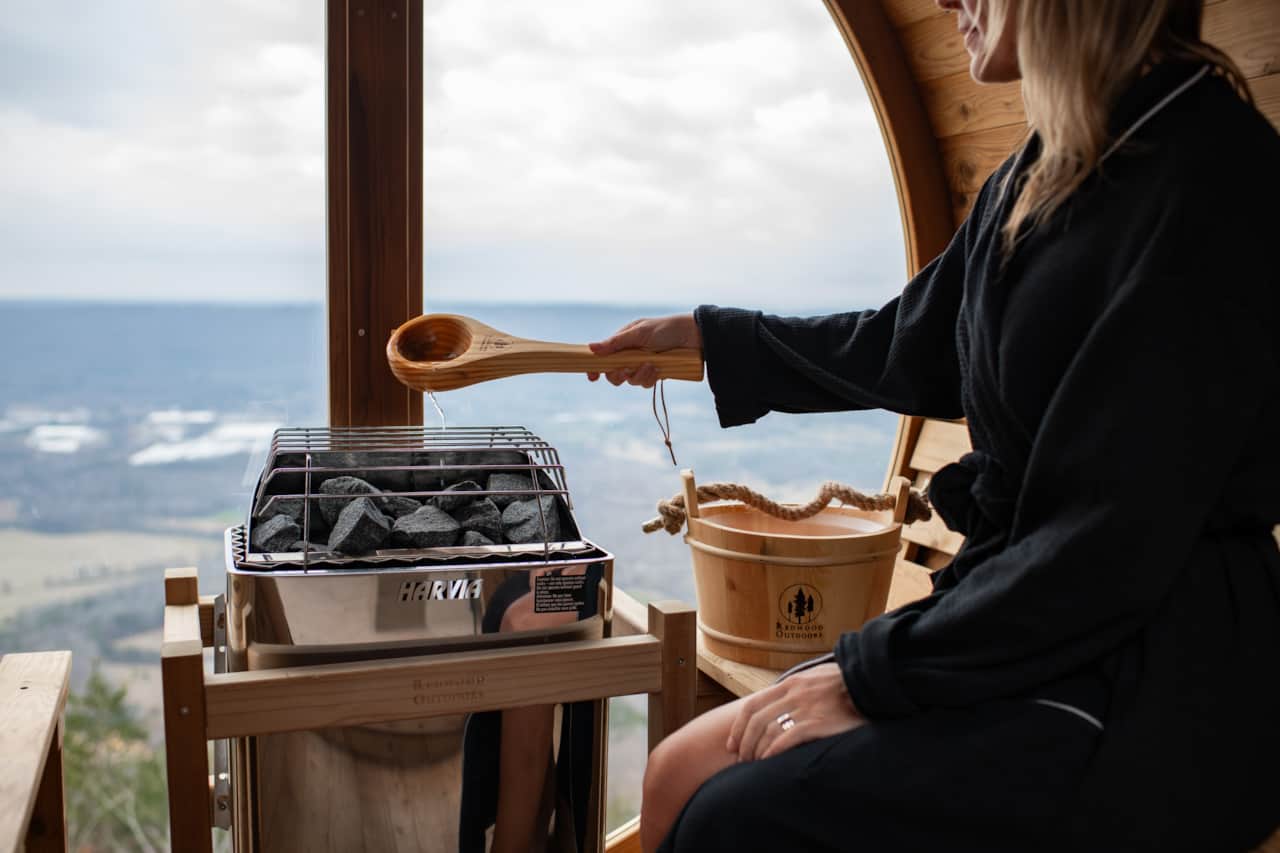 In the barrel sauna, guests tend the coals while soaking in sweeping mountain views.