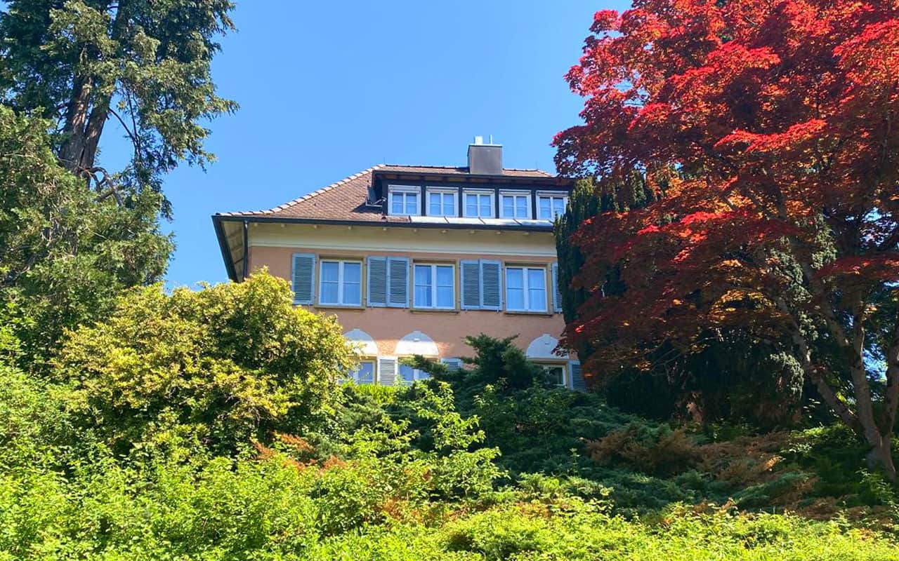 Außenansicht der Ferienwohnung Villa Überlingen mit viel Grün, Büschen und Bäumen.