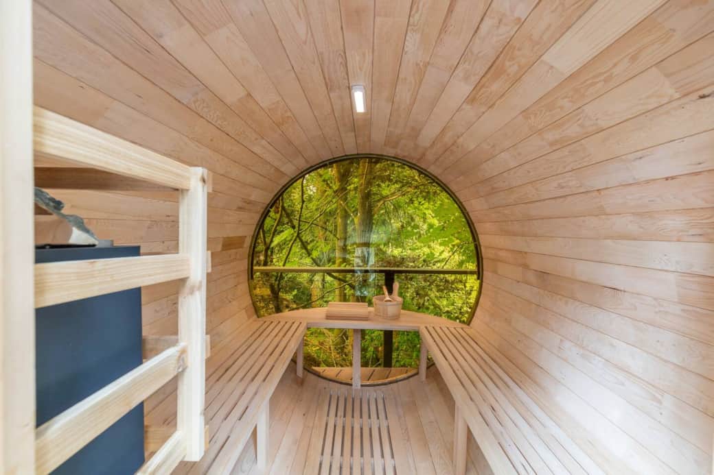 Experience the warmth and serenity inside our cedar barrel sauna, complete with a round forest-view window.