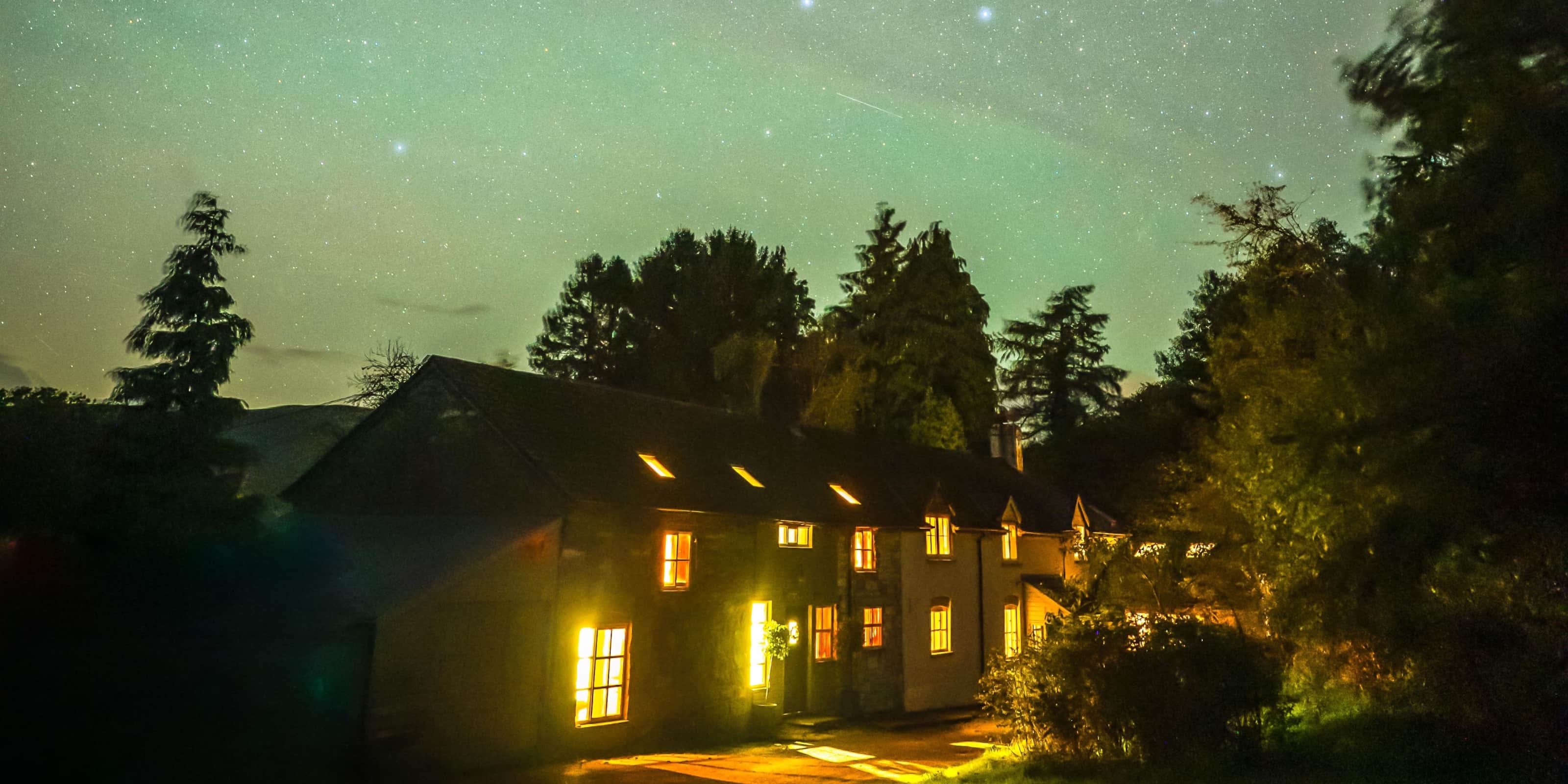 Fronlwyd Longhouse glowing beneath a star-filled Mid Wales sky