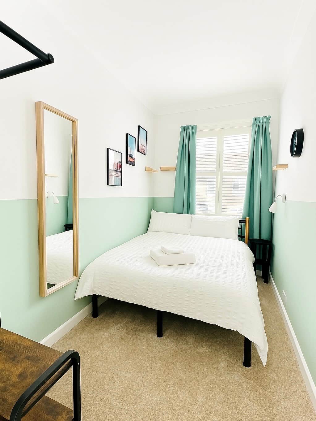 Cozy and bright double bedroom with fresh green accents, plush carpet, and a large window flooding the room with natural light.