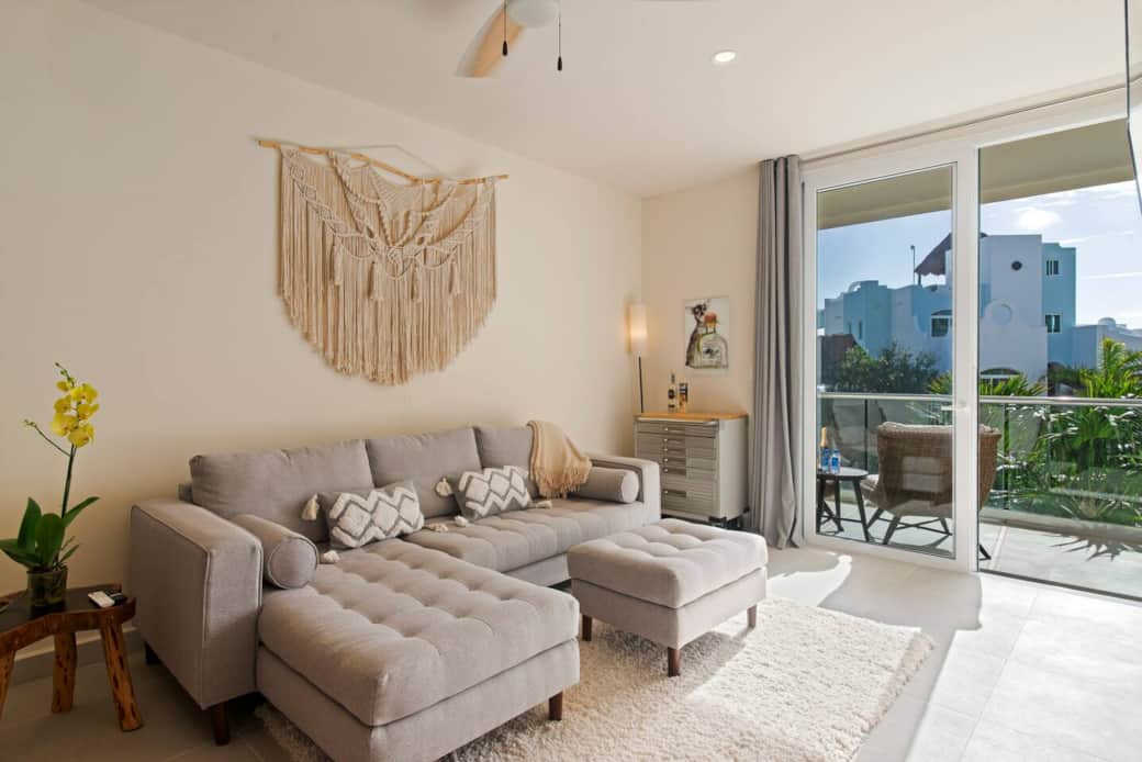 Inviting living room with a couch for an extra guest and a private balcony to enjoy Caribbean Sea views, complete with air conditioning and a ceiling fan for optimal comfort.