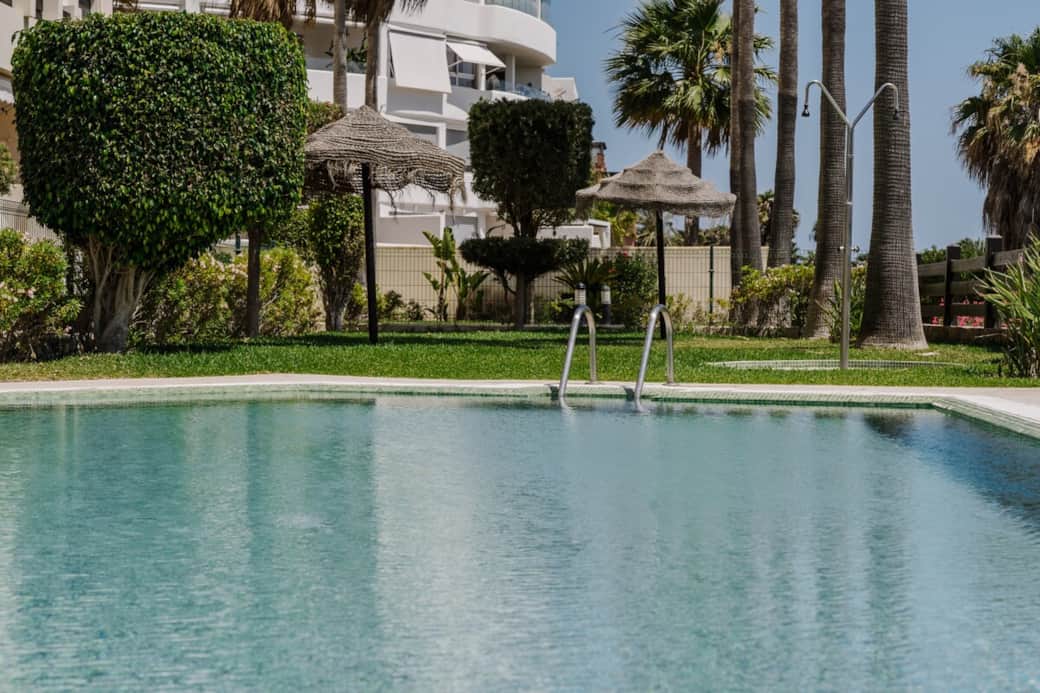 Sumérgete en la tranquilidad de nuestra piscina, rodeada de exuberantes jardines y palmeras que crean un ambiente tropical único. Relájate bajo las sombrillas de paja o disfruta del sol en cómodas áreas verdes. Un espacio perfecto para desconectar