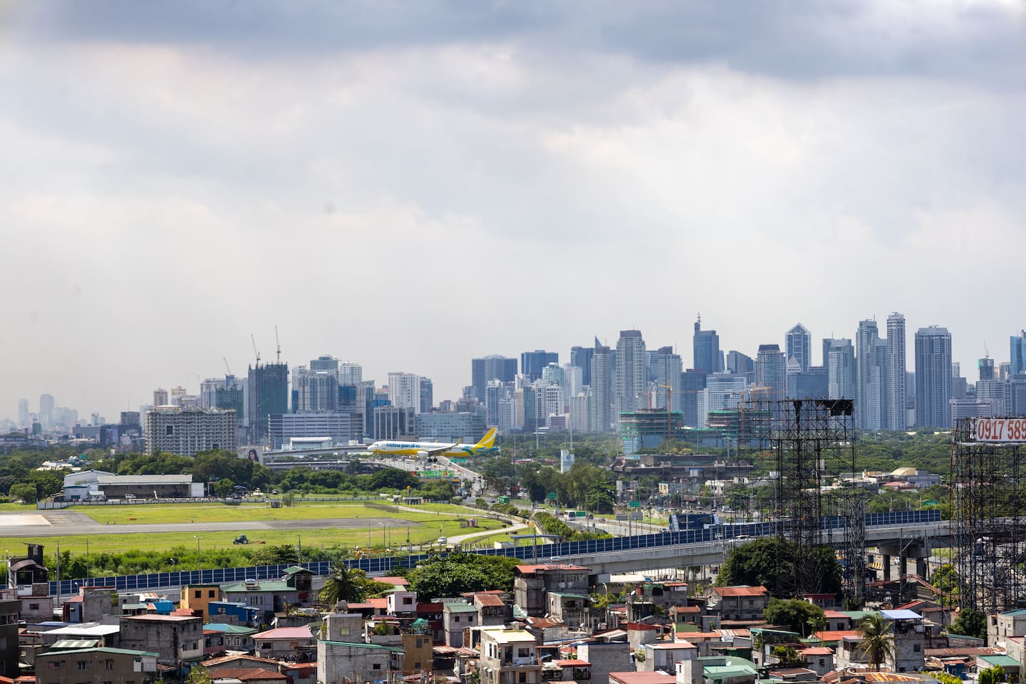 balcony view of Makati skyline with plane landing near NAIA Terminal 3 Manila apartment