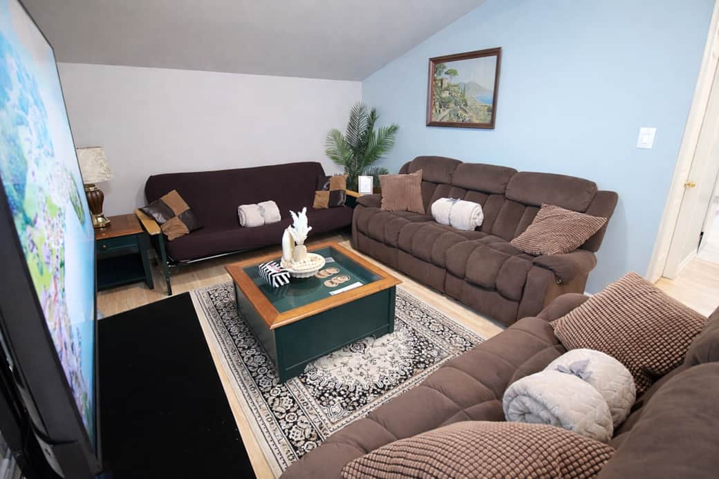 Open-concept living space featuring recliner sofas, large windows, and a 55” smart TV Open-concept living space featuring recliner sofas, large windows, and a 55” smart TV