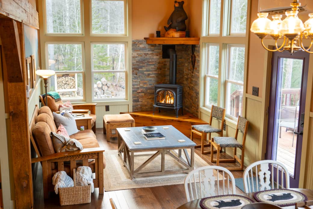 A cozy living room with comfortable seating, a cozy fireplace with stone surround, with large window