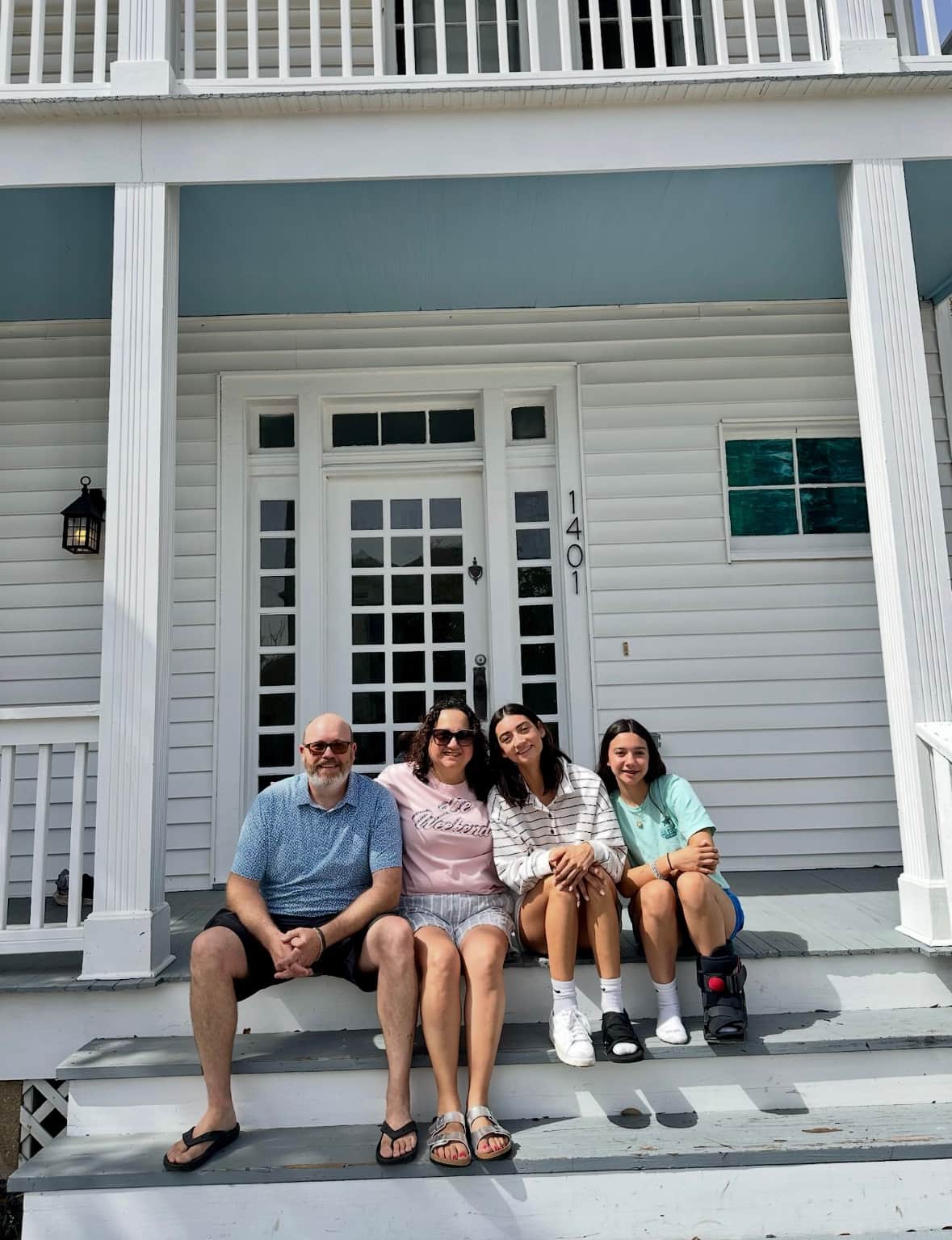 Family sitting on the front porch steps of White Magnolia Galveston during their spring break vacation