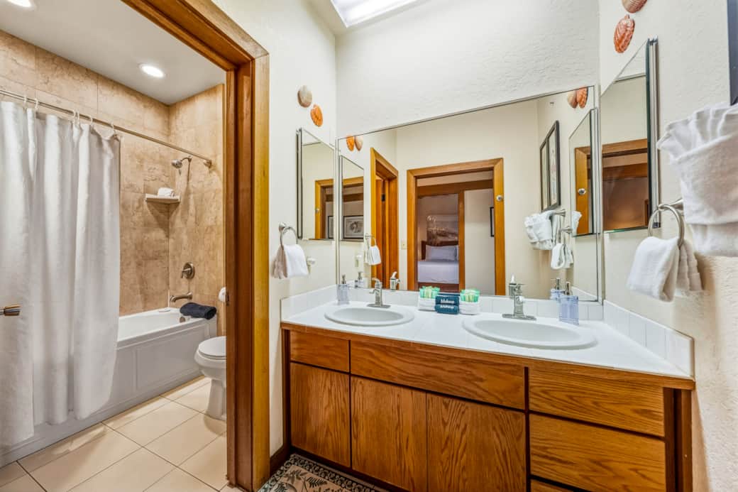 Bright bathroom with double sinks and a tiled shower—spacious and perfect for families.