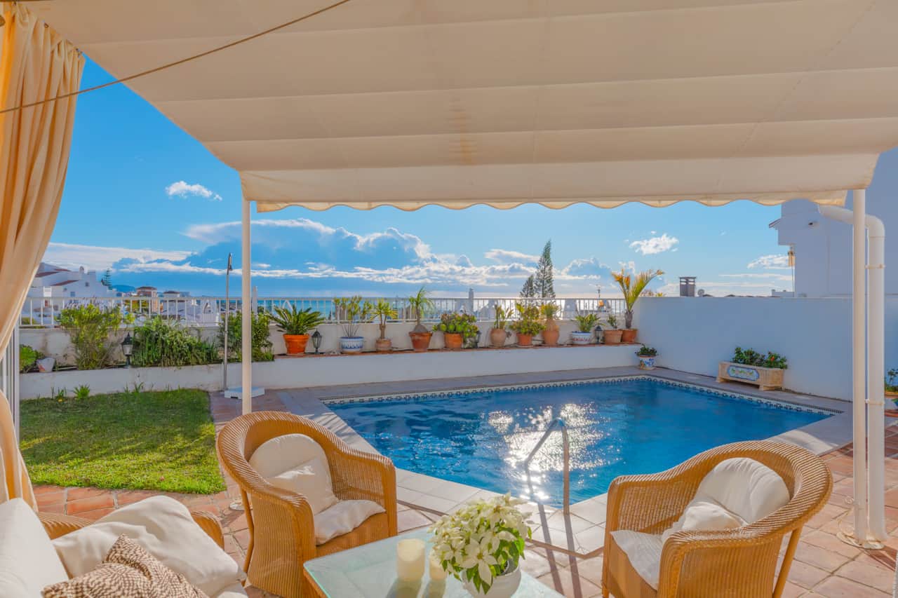 Piscina privada climatizada con tumbonas y vistas al mar.