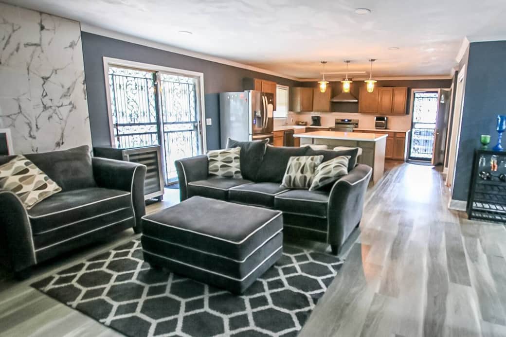 Sink into the plush velvet sofa and piped armchair—your cozy retreat. A versatile ottoman doubles as table or seat. Marvel at the marble-veined accent wall, French doors, and warm pendant glow in this open-plan sanctuary. Sink into the plush velvet sofa and piped armchair—your cozy retreat. A versatile ottoman doubles as table or seat. Marvel at the marble-veined accent wall, French doors, and warm pendant glow in this open-plan sanctuary.