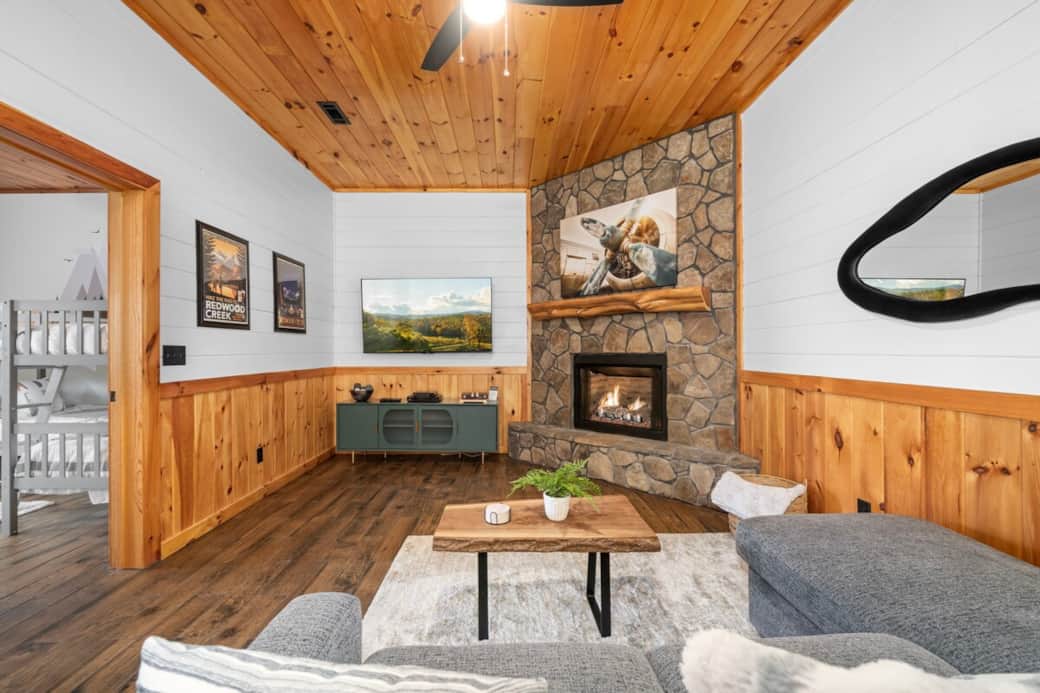 Basement living room with a cozy gas fireplace and a 65" TV powered by high-speed internet—perfect for movie nights. Features a Bose amp for rich sound, Roku OS, Blu-ray player, Dish satellite TV, and hookups for personal gaming systems.
