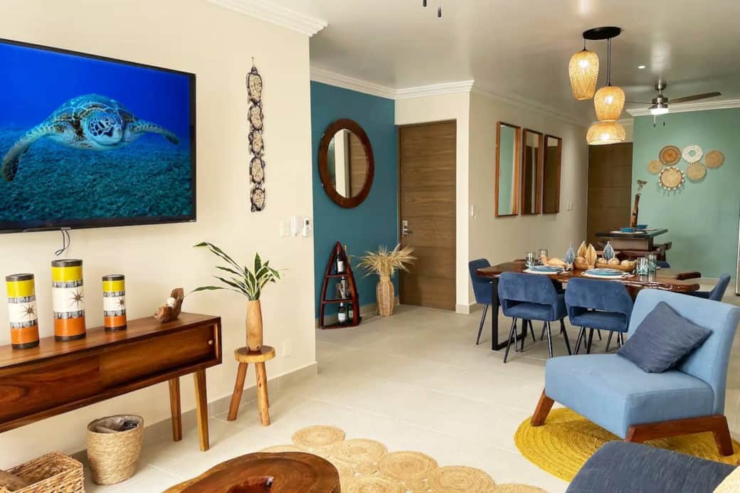 Relax in opulence: Enter our inviting living room featuring a 65-inch TV, a luxurious sofa bed, and chic coffee tables, all complemented by the enchanting ambiance of the lush jungle garden. 